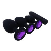 A black, small, silicone plug with a stone, colored amethyst jewel plug is perfect for those starting their journey with silicone