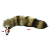 The stainless steel sex toy, with its smooth surface, features a khaki and black, raccoon tail, butt animal, with soft coon fur in brown and black.